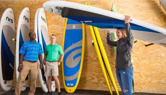 A student being assisted at the CORE equipment facility on campus, where she is obtaining a paddle board